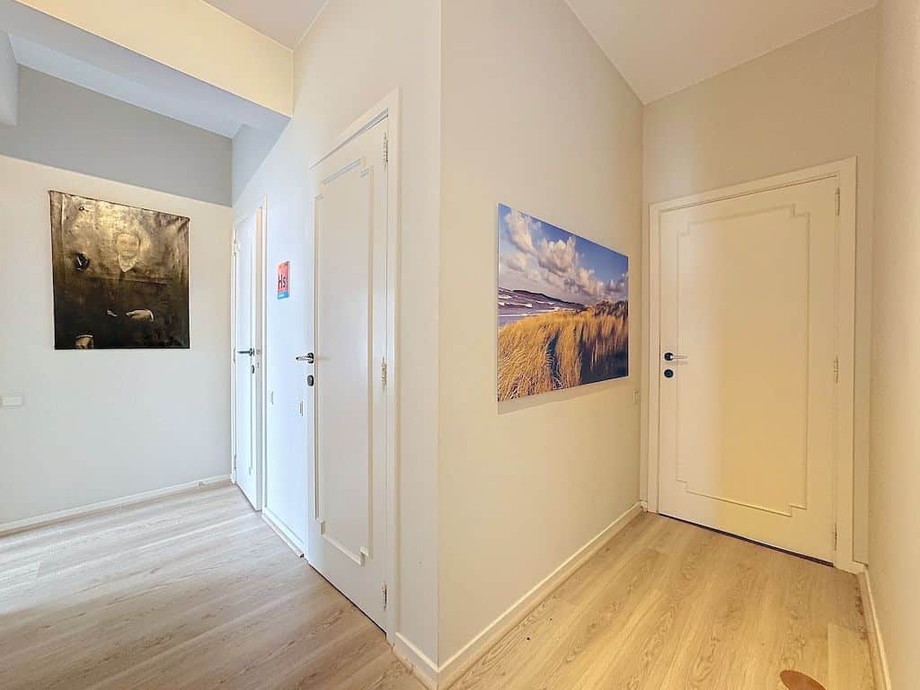 Couloir moderne lumineux avec œuvre abstraite et photo de paysage serein pour une ambiance élégante.