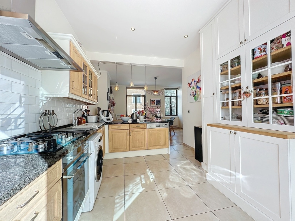 Cuisine moderne lumineuse avec meubles en bois, plans en granit, grande luminosité naturelle et style élégant.