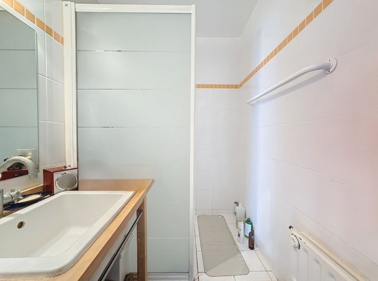 Salle de bain moderne, lumineuse, minimaliste avec baignoire, douche en verre et design épuré.