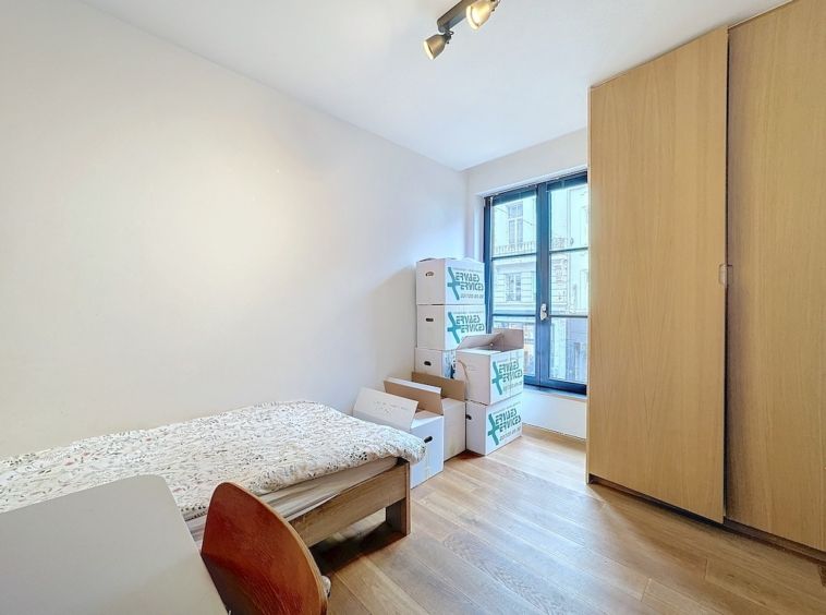 Chambre minimaliste en cours daménagement avec lit simple, bureau et cartons empilés.