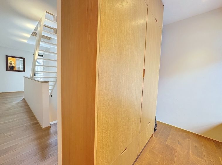 Intérieur contemporain avec meuble en bois, escalier blanc minimaliste et lumière naturelle optimale.