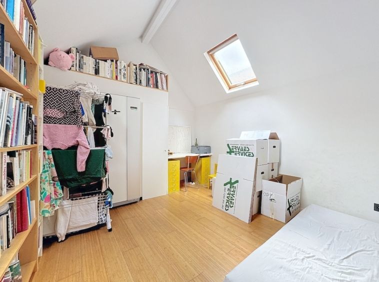 Studio moderne et minimaliste avec bibliothèque, espace de travail et mobilier épuré, lumineux par lumière naturelle.
