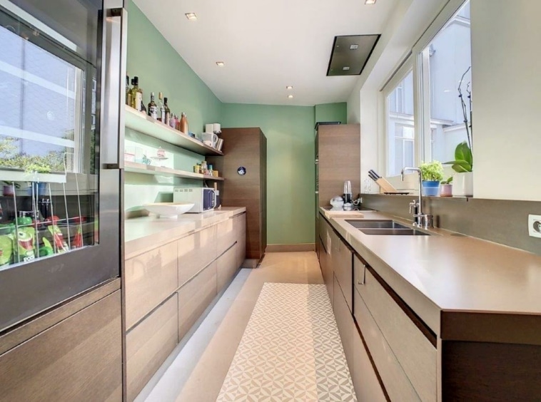 Cuisine moderne avec murs verts, bois chaud, électroménagers intégrés et plantes naturelles