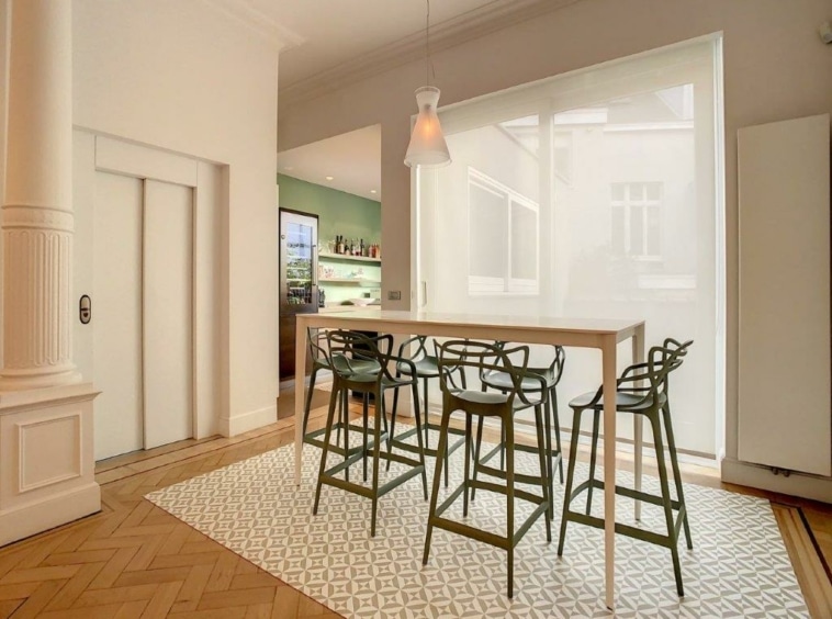 Salon moderne avec table en bois, tabourets verts et cuisine lumineuse à accessoires verts