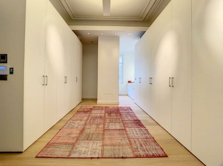 Couloir moderne minimaliste avec murs blancs, tapis chaud et éclairage doux naturel.