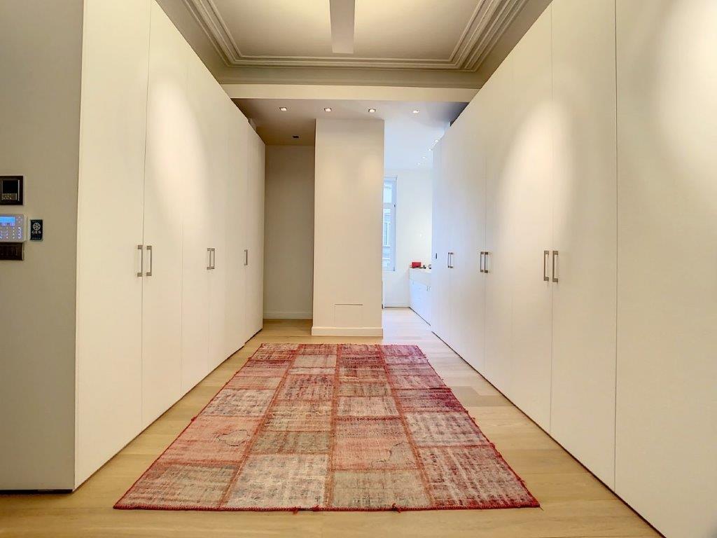 Couloir moderne minimaliste avec murs blancs, tapis chaud et éclairage doux naturel.