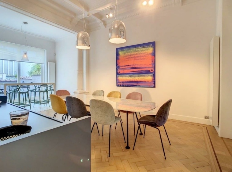 Salle à manger moderne avec mobilier coloré, art abstrait, lumière naturelle et ambiance chaleureuse.