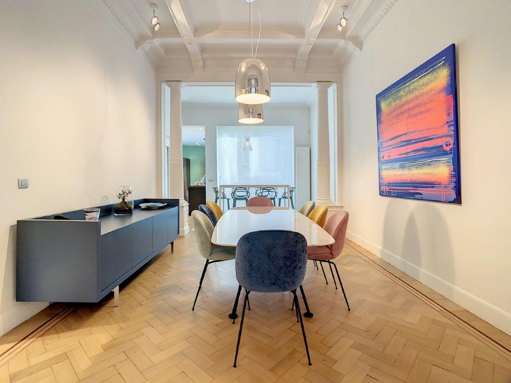 Salle à manger moderne avec parquet à chevrons, mobilier coloré et art dynamique.