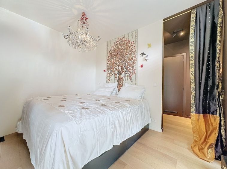 Chambre cosy et élégante avec murale arbre, chandelier, rideaux dorés et décoration moderne.