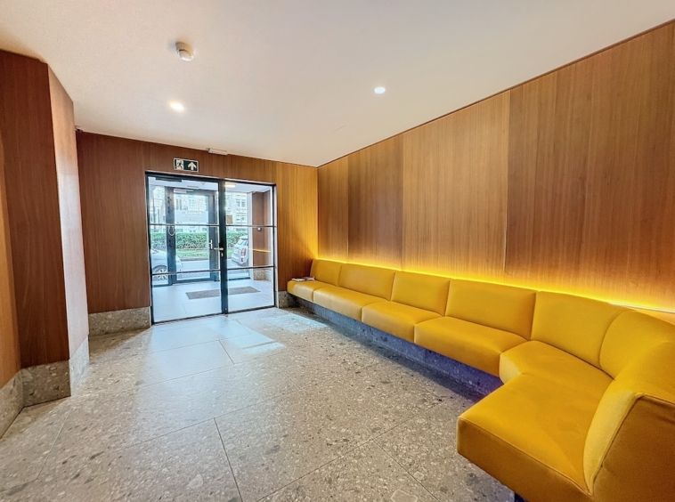 Intérieur moderne avec canapé jaune, lumière douce, murs en bois, ambiance élégante et accueillante.