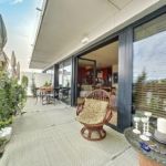 Terrasse urbaine moderne, espace détente élégant avec vue, mobilier chic et plantes verdoyantes.