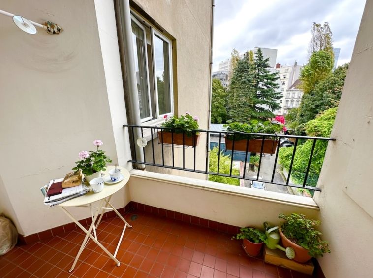 Balcon urbain cozy avec plantes, table blanche, vue moderne, parfait pour détente et lecture.