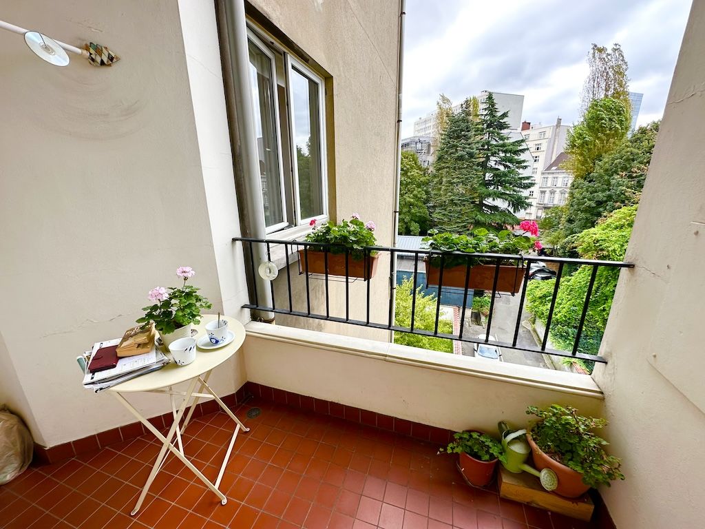 Balcon urbain cozy avec plantes, table blanche, vue moderne, parfait pour détente et lecture.