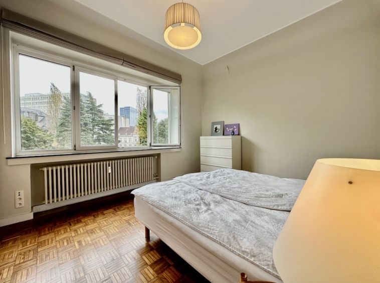 Chambre lumineuse et épurée avec lit cosy, parquet en bois et décoration minimaliste.