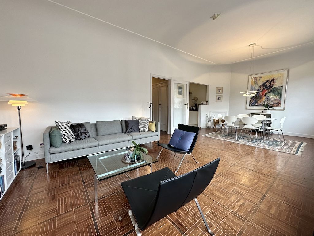 Salon moderne et lumineux avec canapé gris, mobilier élégant et espace dining convivial.