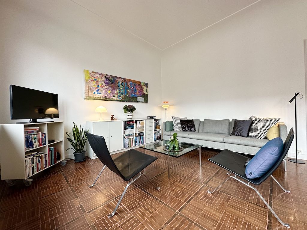 Salon moderne minimaliste avec canapé gris, mobilier élégant, décoration colorée, ambiance chaleureuse et épurée.