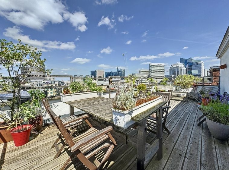 Terrasse urbaine avec vue panoramique, mobilier en bois et plantes vertes, idéale pour se détendre.