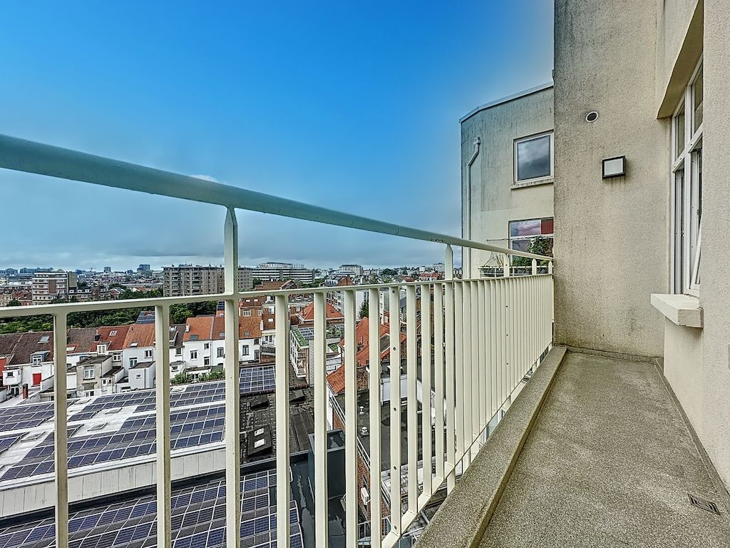 Balcon urbain écologique avec vue sur toits colorés et panneaux solaires modernes, ciel bleu lumineux.