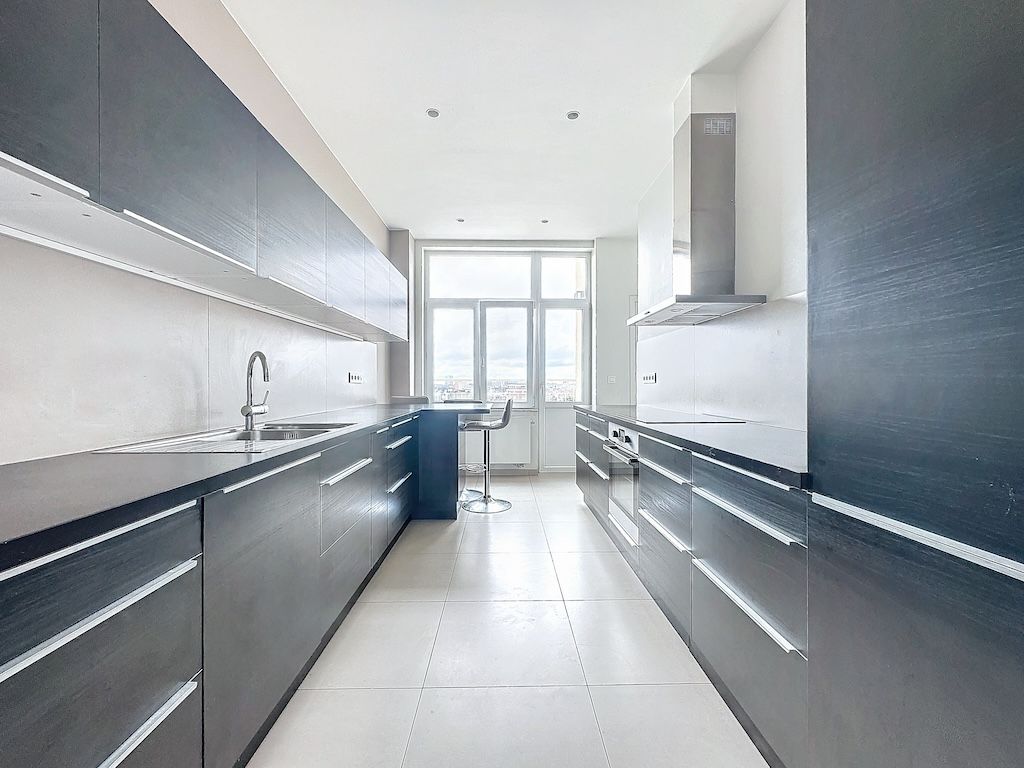 Cuisine moderne minimaliste avec grands rangements noirs, lumière naturelle et espace convivial.