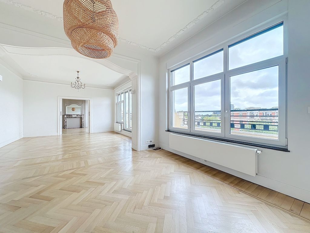 Salon lumineux moderne avec parquet en chevrons, luminaire en osier et grands fenêtres.