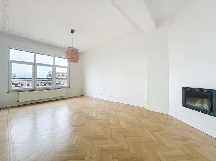 Salon lumineux moderne avec cheminée, lampe corail, murs blancs et vue urbaine.