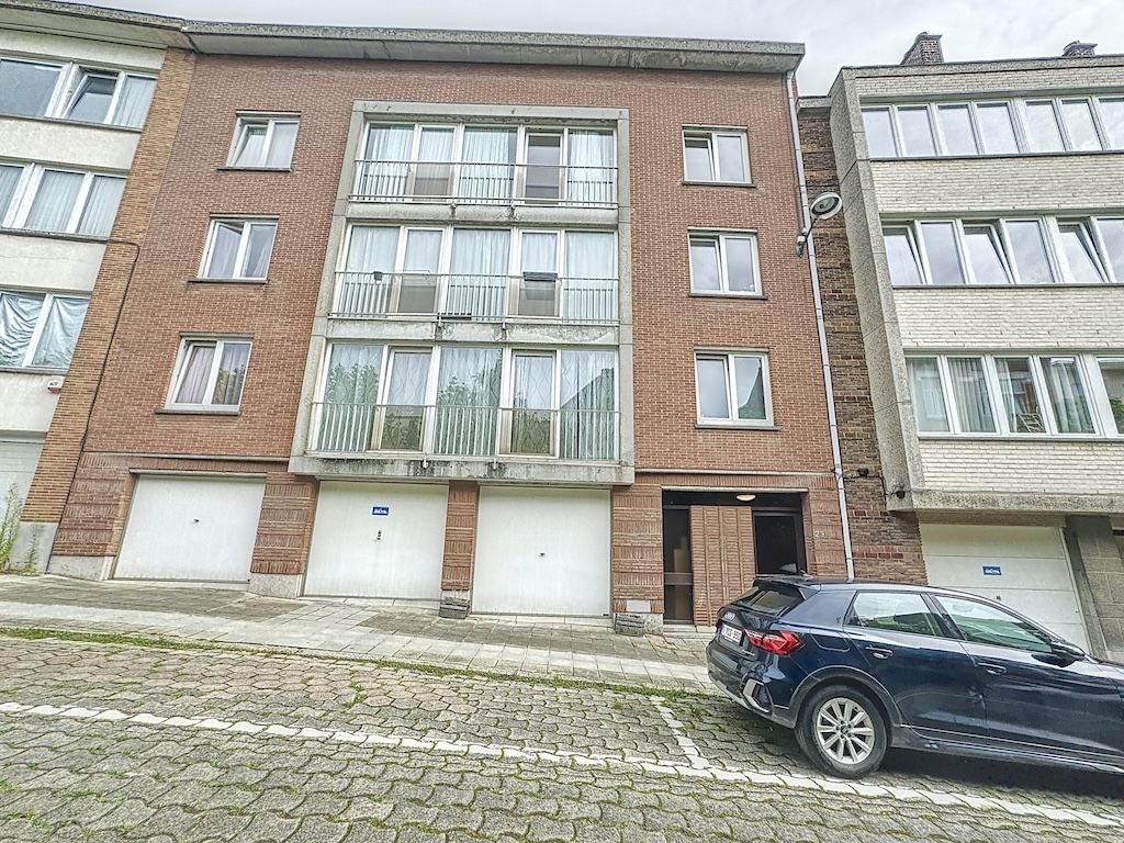 Immeuble résidentiel moderne en briques, grande fenestration, rue pavée calme et élégante.