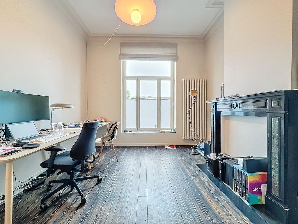 Bureau lumineux moderne avec cheminée, mobilier épuré, grande fenêtre et ambiance calme et productive.