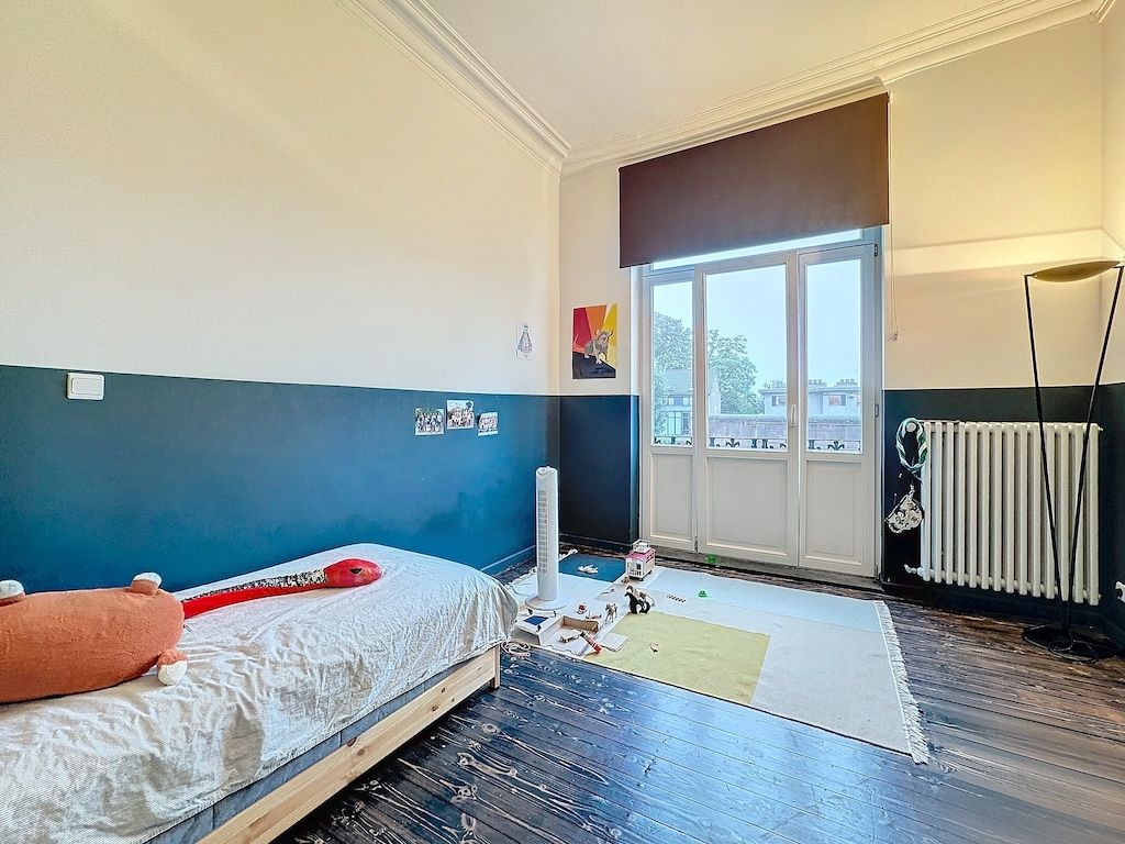 Chambre enfant minimaliste lumineuse avec lit, espace de jeux et décoration colorée.