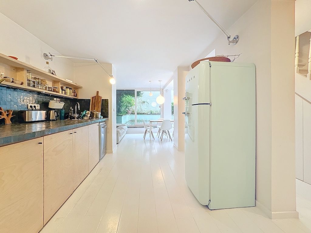 Cuisine moderne lumineuse avec frigo rétro vert menthe et espace repas avec vue sur jardin