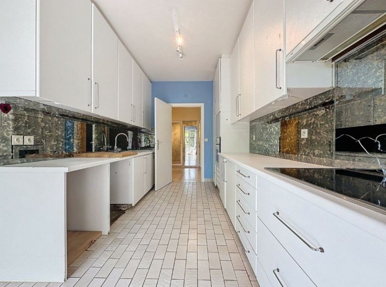 Cuisine contemporaine épurée avec meubles blancs, backsplash sombre et sol lumineux.