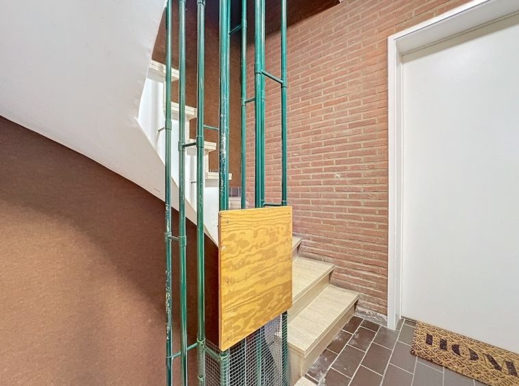 Escalier moderne en bois et métal vert dans intérieur contemporain minimaliste avec sol en carreaux foncés.