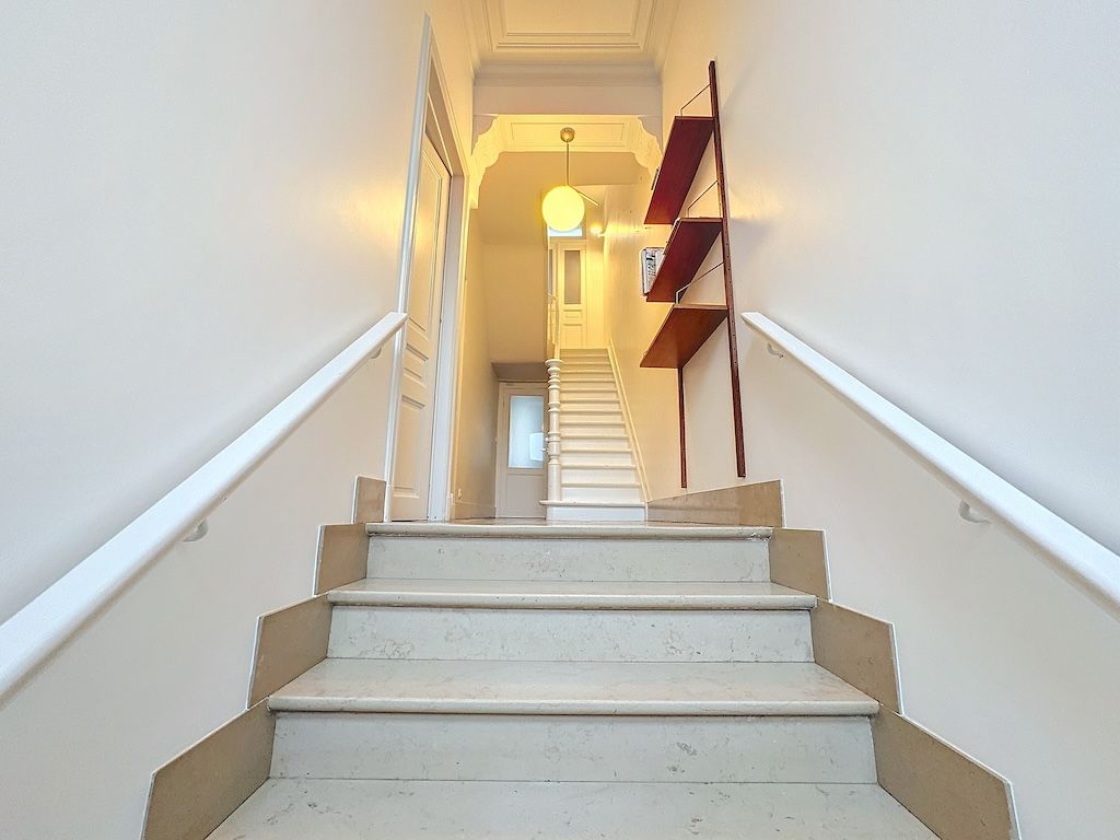 Escalier moderne en pierre claire, lumineux, avec passage blanc et décoration minimaliste.
