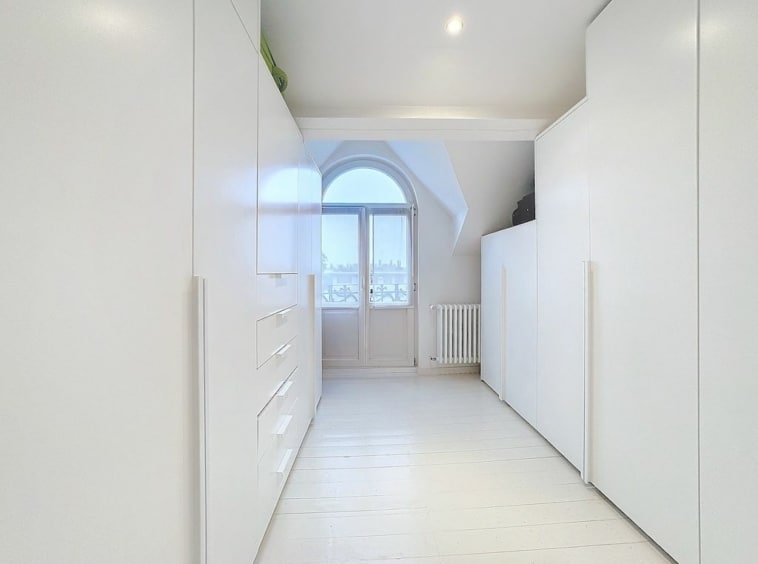 Couloir moderne blanc avec lumineuses fenêtres en arche, mobilier épuré et sol en bois chaleureux.