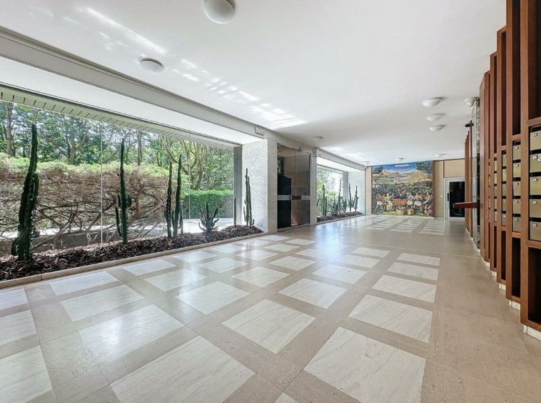Intérieur moderne lumineux avec vue sur la nature, mur artistique et rangements en bois chaleureux.