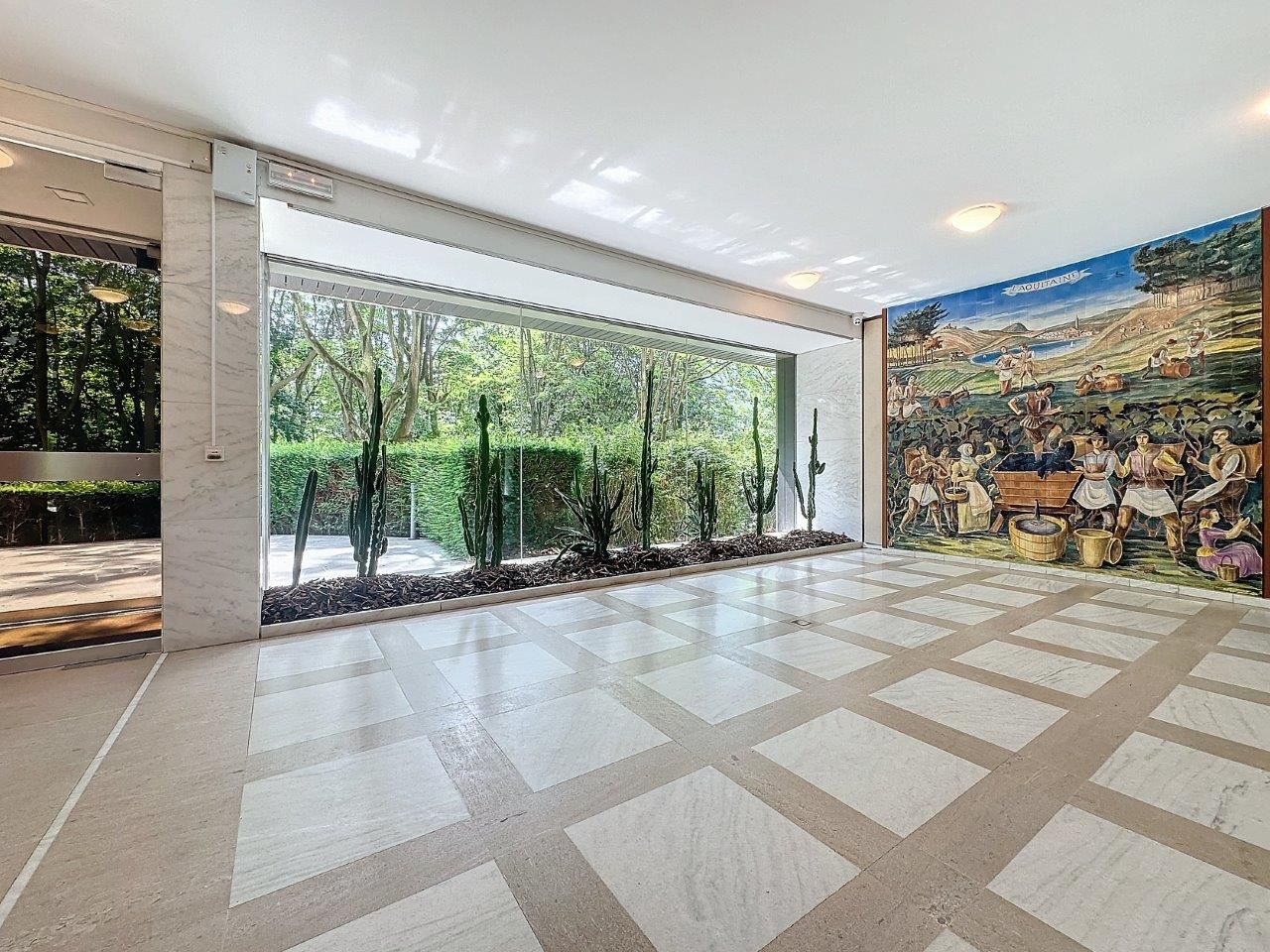Intérieur moderne avec murale colorée, vue sur la nature et sol en pierre polie élégante.