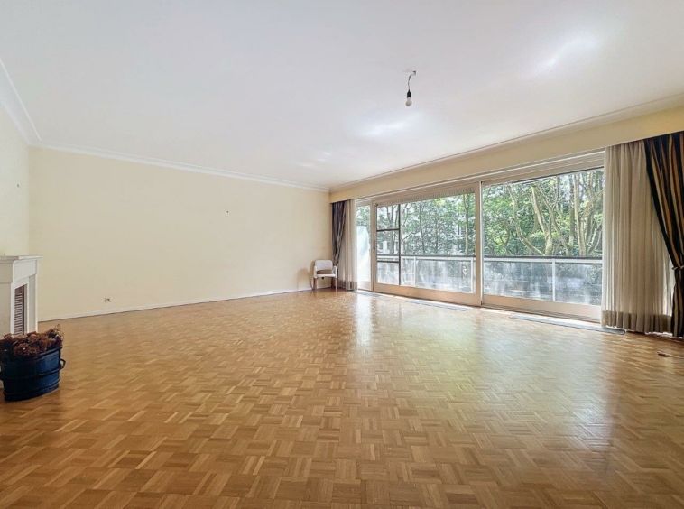 Salon lumineux et convivial avec parquet, cheminée, vue sur la nature et coin lecture cosy