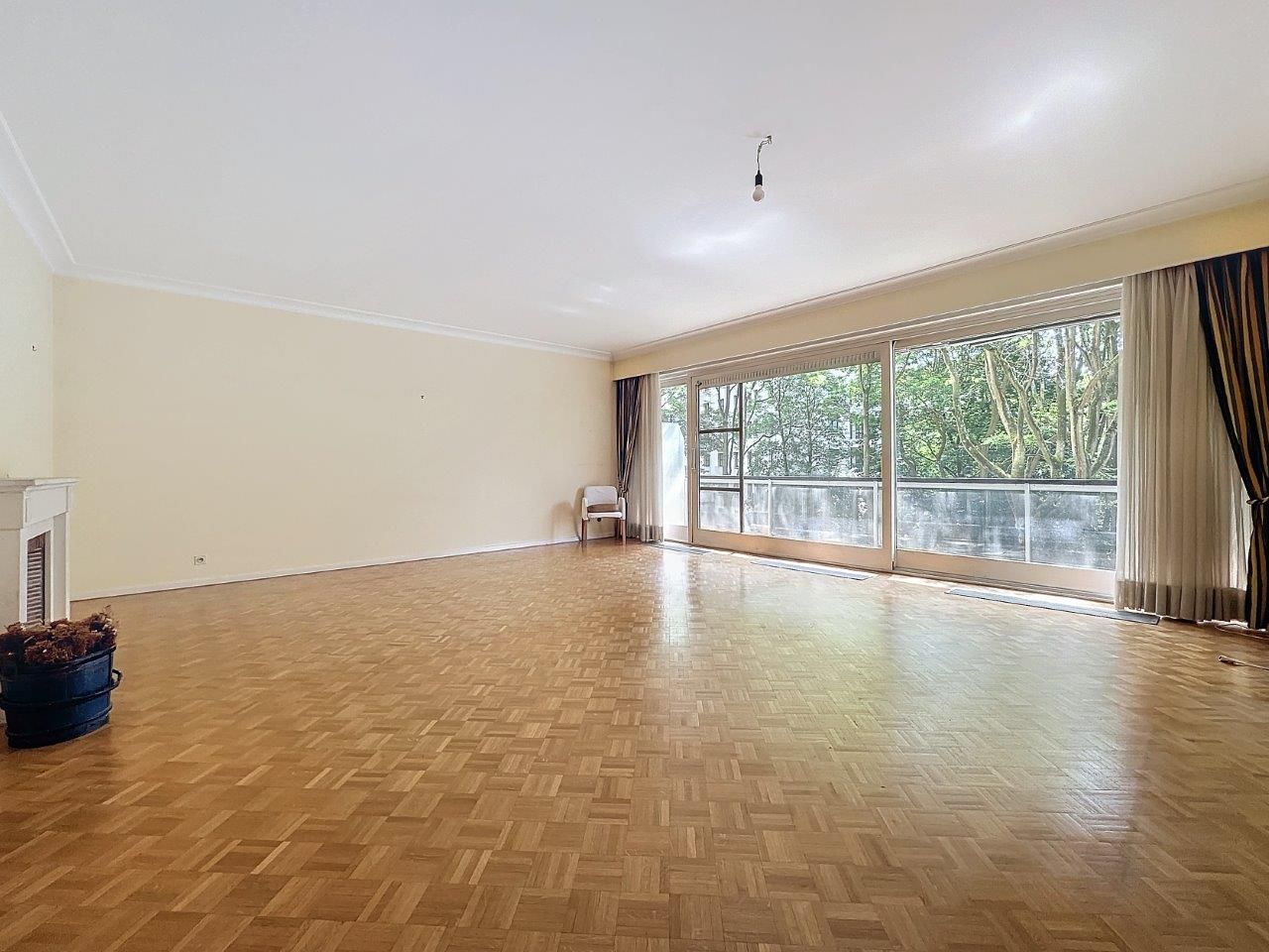 Salon lumineux et convivial avec parquet, cheminée, vue sur la nature et coin lecture cosy
