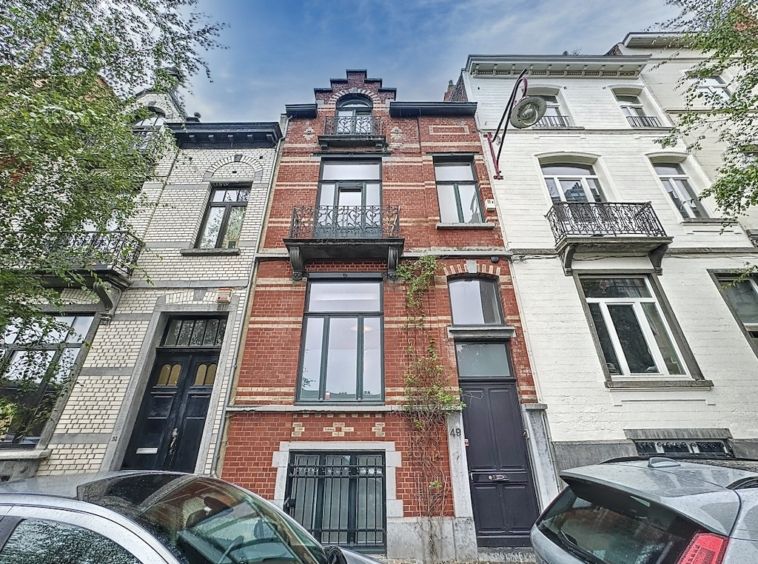 Rues urbaines avec maisons en brique, pierre, et modern style, entourées d’arbres et véhicules.