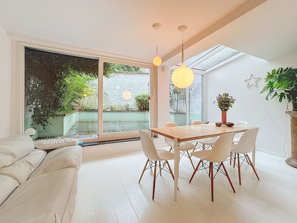 Salle à manger lumineuse avec vue extérieure, mobilier moderne, éclairage élégant et décoration minimaliste.