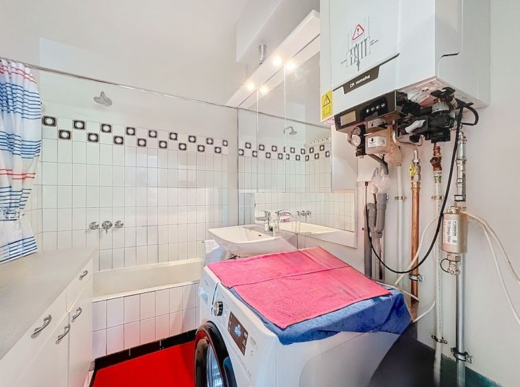 Coin laverie moderne avec baignoire, plan blanc, accents colorés et design épuré.