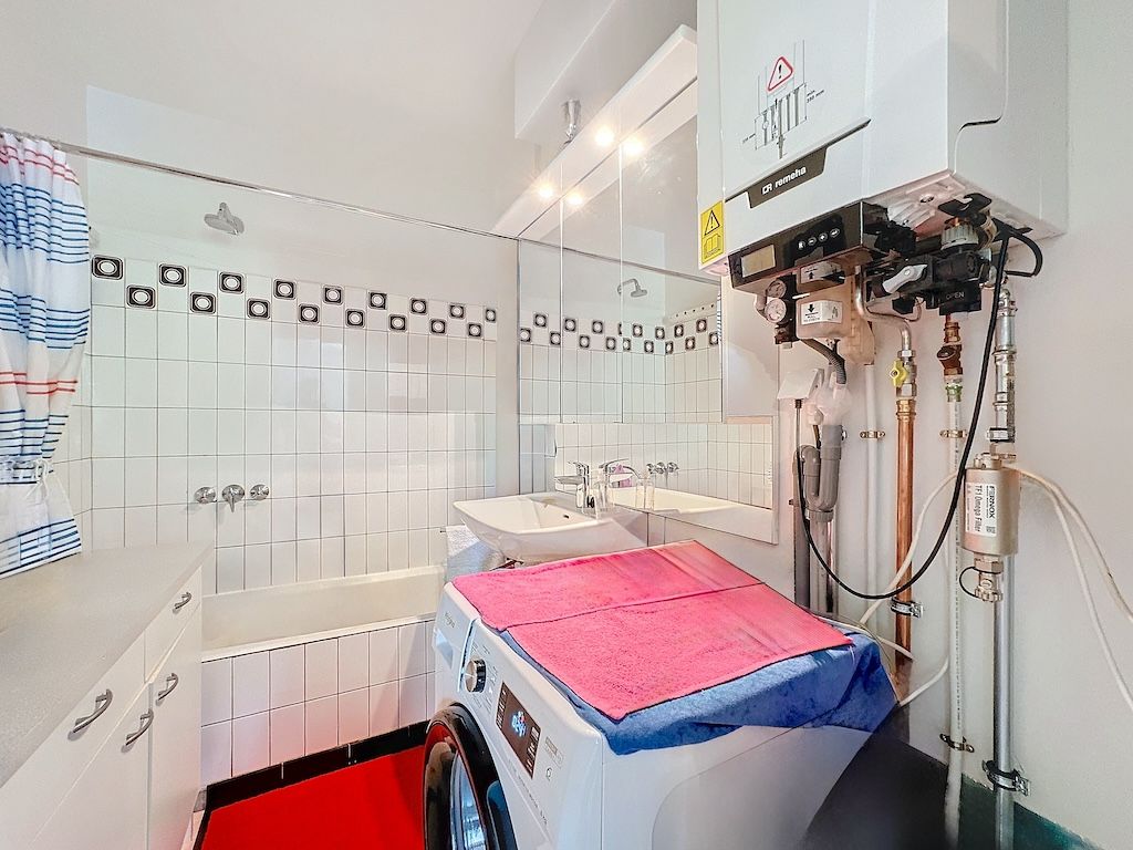 Coin laverie moderne avec baignoire, plan blanc, accents colorés et design épuré.