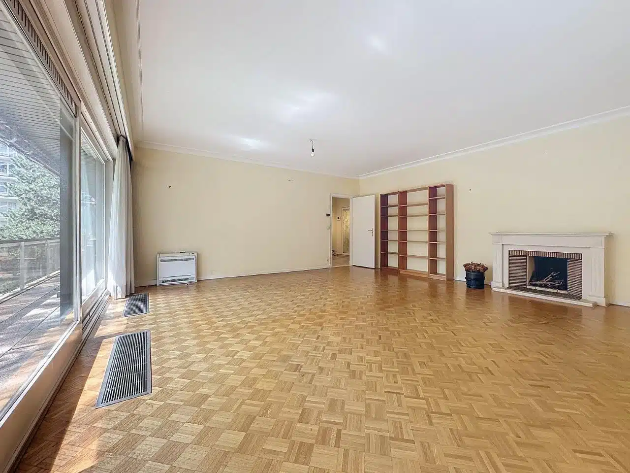 Lichte woonkamer met open haard en traditionele parketvloer Woonkamer - 2 slaapkamer appartement met terrassen en garage - Ukkel