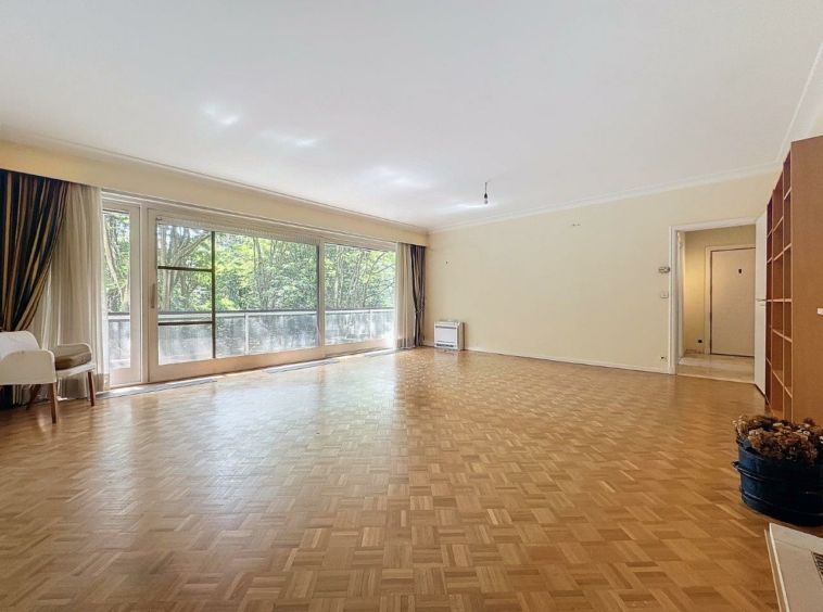 Salon lumineux avec grandes fenêtres, parquet clair, mobilier minimaliste et ambiance apaisante.