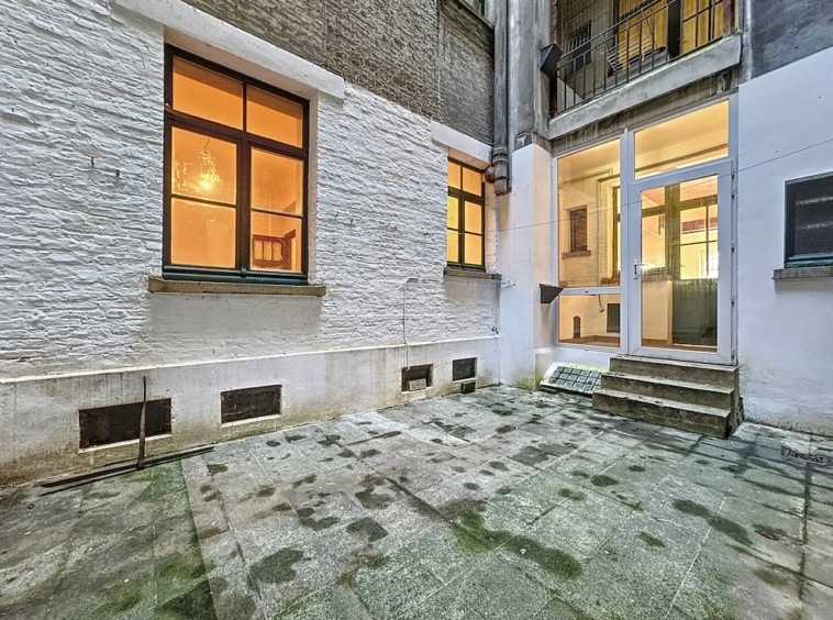 Cour intérieure chaleureuse avec escalier, fenêtres en bois, murs en stuc patinés et ambiance nostalgique.