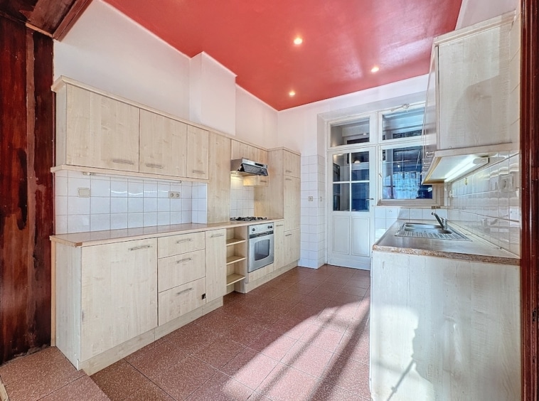 Cuisine moderne avec murs colorés, bois clair, plan en granit lumineux et grande fenestration.