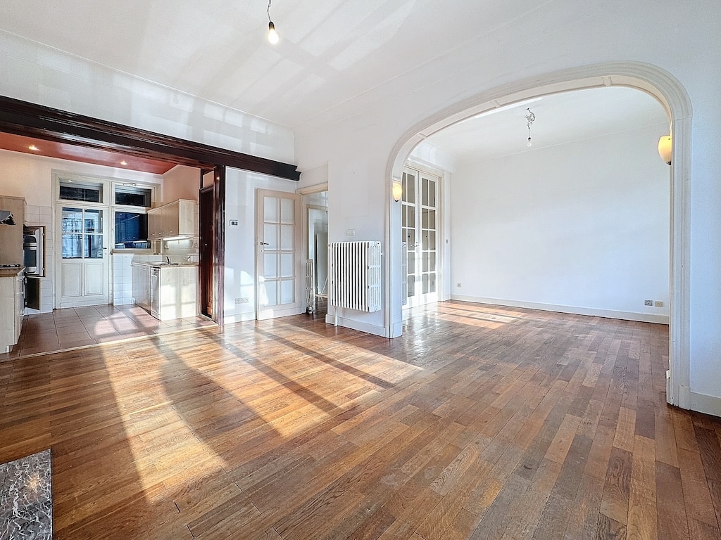 Espace lumineux avec plancher en bois, cuisine moderne et archways élégants pour décoration.