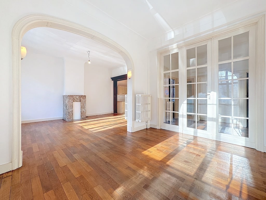 Salon lumineux avec cheminée, arches élégantes et portes-fenêtres donnant accès à lextérieur.