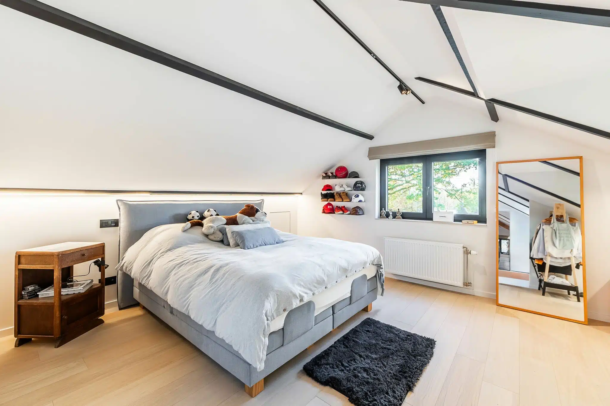 Chambre moderne minimaliste avec lit, lumière naturelle, poutres apparentes et décoration élégante.