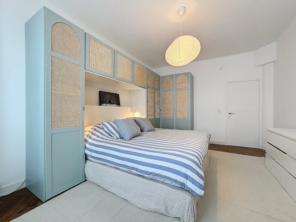 Chambre moderne et naturelle avec lit bleu et lumière chaleureuse pour un espace relaxant.