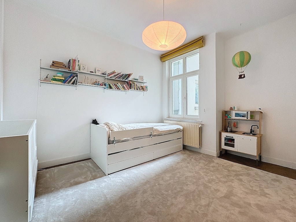Chambre minimaliste et lumineuse, avec lit moderne, étagère de livres, décoration originale et ambiance sereine.